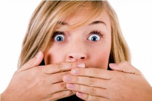 Closeup of young women covering her mouth with both hands on a white isolated background